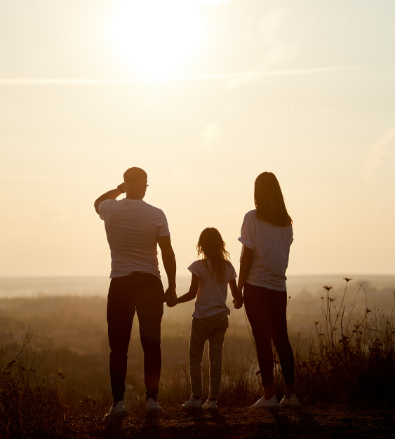 family standing on a hill at golden horizon