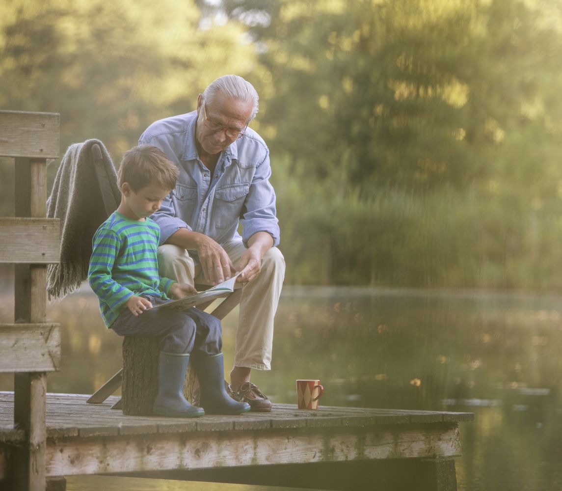 grandfather-and-grandson-reading-at-lake-555799527-5ac7c84143a1030036c1b221